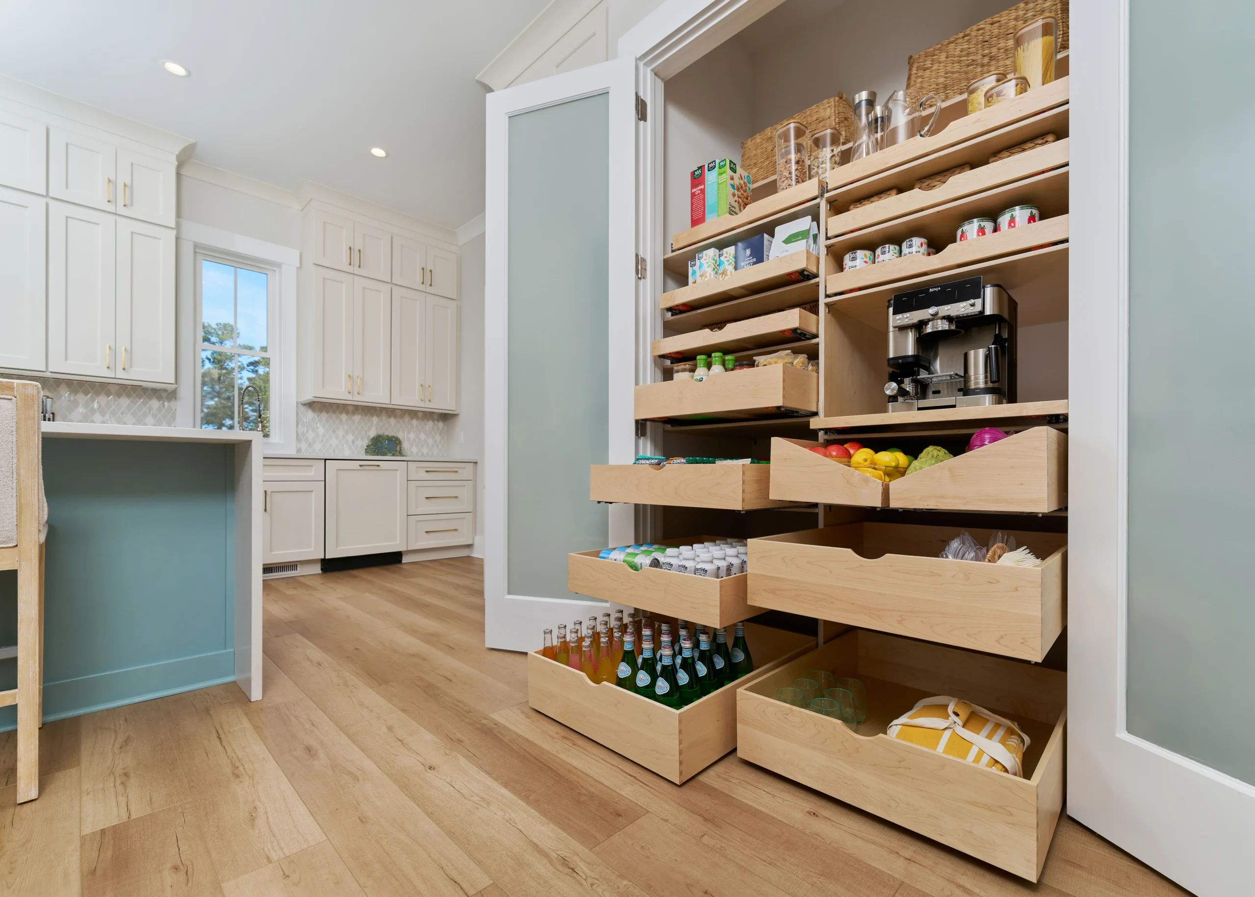 An open pantry with pull-out shelves and drawers filled with various food items and a coffee maker An open pantry with pull-out shelves and drawers filled with various food items and a coffee maker